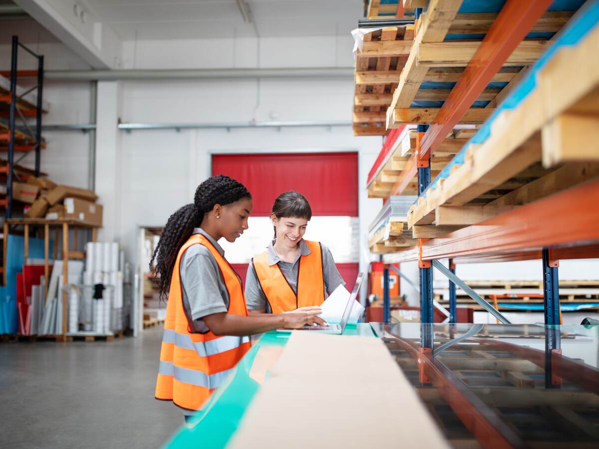 multi ethnic women workers working in a warehouse with a laptop.